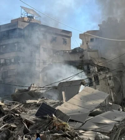 Una mujer camina entre edificios dañados y escombros tras un ataque, en medio de las hostilidades en curso entre Hezbolá y las fuerzas israelíes.