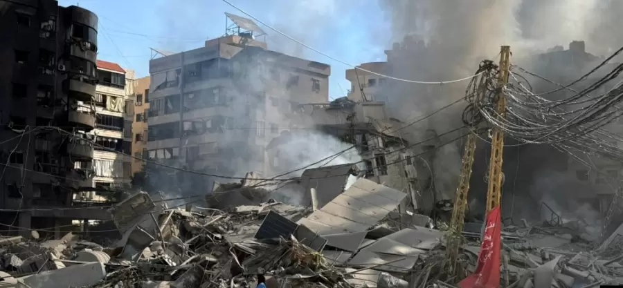 Una mujer camina entre edificios dañados y escombros tras un ataque, en medio de las hostilidades en curso entre Hezbolá y las fuerzas israelíes.