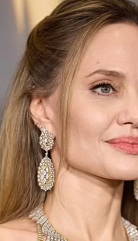 Llevaba muchas joyas llamativas, incluido un collar enorme y pendientes colgantes.