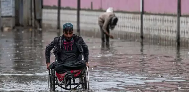 Una persona con discapacidad trata de sobreponerse a una inundación.