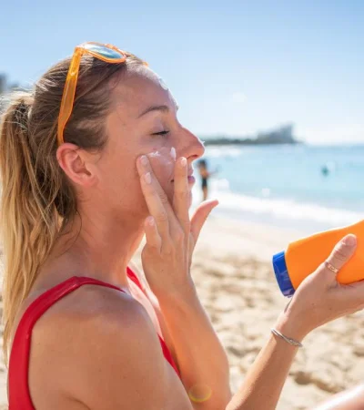 una-mujer-aplicandose-protector-solar-facial en la playa/