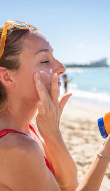 una-mujer-aplicandose-protector-solar-facial en la playa/
