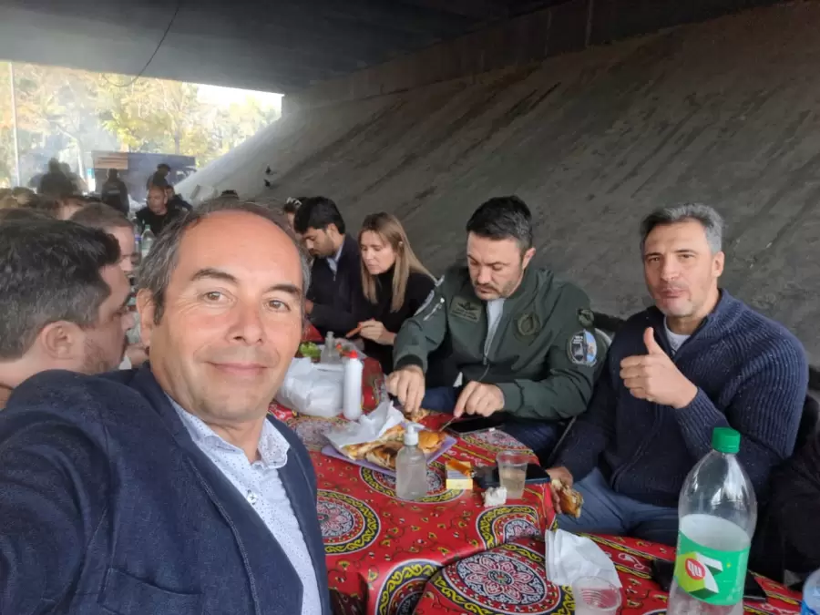 El ministro de Defensa, Luis Petri junto con el concejal Jorge Magnaghi comiendo choripanes en el puesto que está cercano a la cancha del Tomba