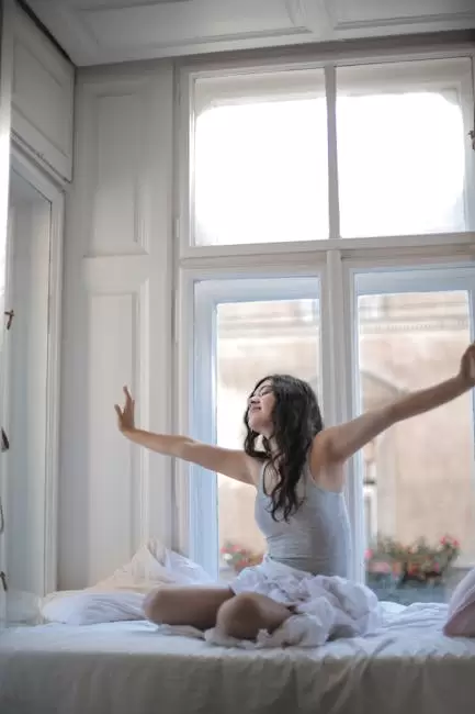 Foto De Mujer En Camiseta Sin Mangas Gris Mientras Está Sentada En La Cama