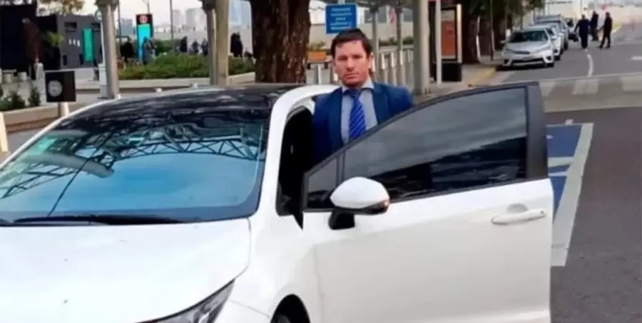 Sebastián Matías Palacios, junto al auto que apareció incinerado en Córdoba.