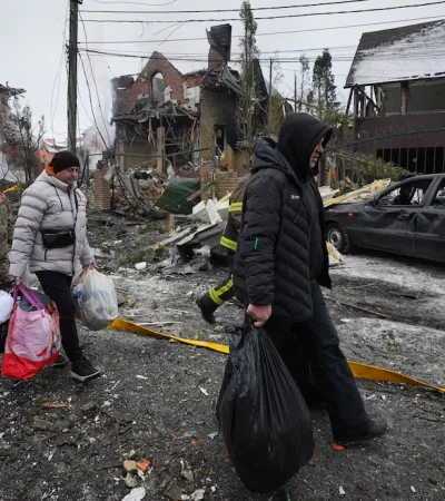 Residentes abandonan sus hogares con sus pertenencias tras un ataque de drones ruso que dañó edificios en Kiev.